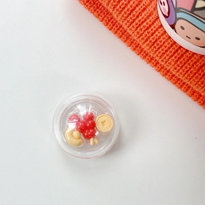 Detail of a clear sphere phone grip featuring miniature red hawthorns and gold coins inside