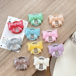 Glitter bow phone grip stands in ten assorted colors on a wooden desktop display