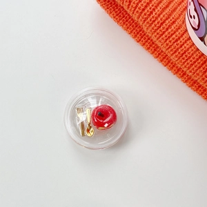 Macro detail of miniature apple food model with golden utensils in a clear round case