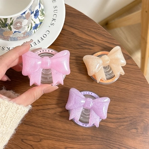 Glittering bow-shaped phone grip stand in pink, beige, and purple resin with gift text