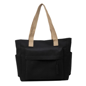 Black canvas tote bag featuring contrast cream handles and a large front flap pocket