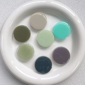 Macro view of colorful glossy round pop socket grips for phones in a white ceramic dish