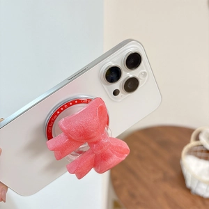 Close-up of pink glitter bow phone grip with Gift For You print on a white smartphone