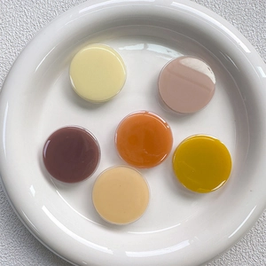 Top view of six colorful circular resin phone socket accessories in a white dish