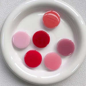 Close-up of 6 round gradient resin phone grip buttons on a minimalist white ceramic plate