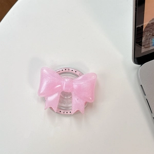 Detailed view of pink bow phone grip with glitter finish on a minimalist desk