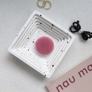 Minimalist square plaster tray with black ink splatter and pink phone socket grip