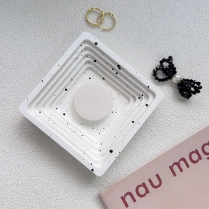 Macro view of square white stepped jewelry tray with black speckled ink pattern