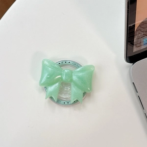 Detail view of mint green glittery bow phone grip holder on a white desk setup