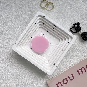 Detail shot of white terrazzo style tray and pink round phone stand on lifestyle background