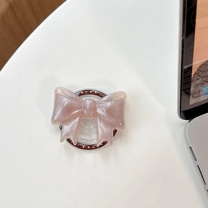 Detail shot of a pink glitter bow phone grip stand on a white minimalist desktop