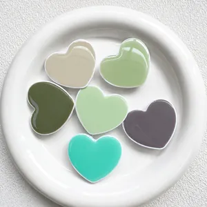 Close-up of Morandi colored heart-shaped phone grips arranged on a white ceramic plate