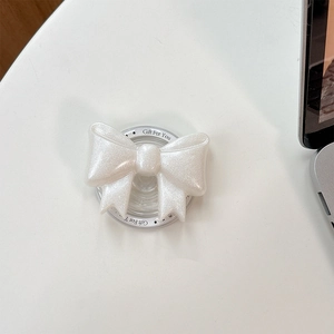 Close-up of a white glittery bow phone socket holder on a minimalist desk background