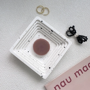 Macro shot of a dusty pink circular phone grip on a textured white display tray