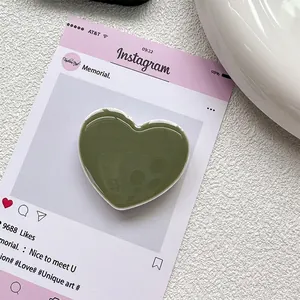 Détail du support de téléphone en forme de cœur vert olive avec finition lisse et base blanche