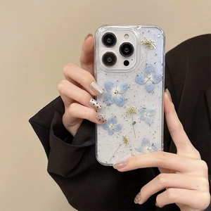 Detailed view of clear iPhone case with blue dried flowers and silver glitter flakes