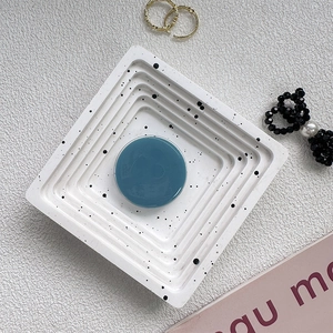 Macro view of Morandi blue circular phone grip stand on a designer speckled tray