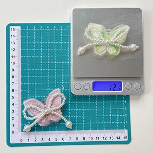 Macro view showing dimensions and 12.1g weight of embroidered pearl bow phone grip