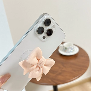 Close-up of a pink ribbon bow collapsible phone grip on a white smartphone in hand