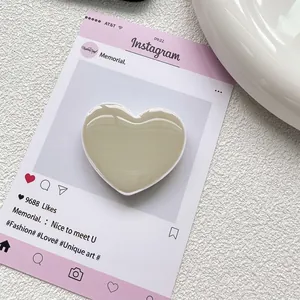 Gros plan du support de téléphone beige en forme de cœur avec finition en résine brillante