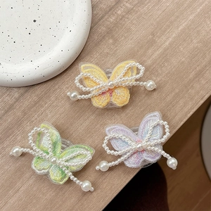 Detailed view of pearl-beaded butterfly phone sockets with intricate embroidery on wood