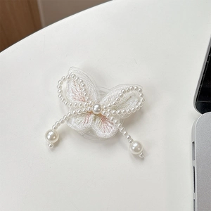 Macro shot of white embroidered butterfly phone grip with faux pearl beads on a white desk