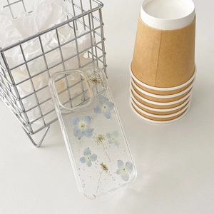 Detail of transparent iPhone case with embedded blue dried flowers and silver foil flakes