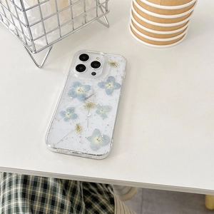 Detail of transparent iPhone case featuring real blue dried flowers and silver foil flakes