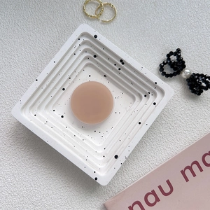 Detail view of a matte nude round phone grip stand placed on a modern white spotted tray