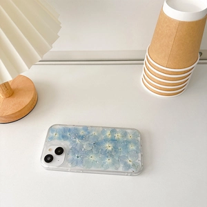 Detailed view of clear iPhone case with blue dried flowers and silver foil flakes