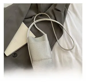 Detail showing silver litchi grain leather texture and slim strap of the crossbody bag