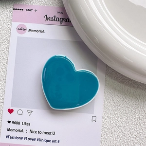 Gros plan d'un support de téléphone bleu brillant en forme de cœur sur une assiette