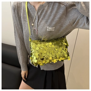 Detail of bright green sequin crossbody bag styled with grey cardigan and black skirt
