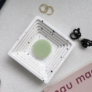 Flat lay of a light green round phone socket holder on a marble textured tray