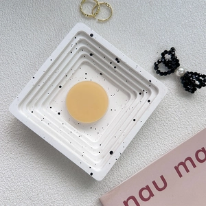 Flat lay of a round solid perfume on a white speckled tray with elegant lifestyle props