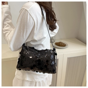 Detail of a chic black sequined pillow bag with large round metallic discs and leather strap
