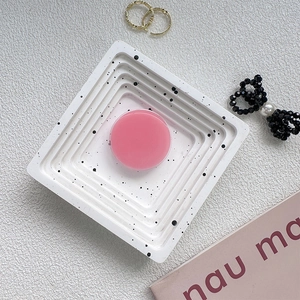 Close-up of a pink round phone grip on an artistic white tray with black marble patterns