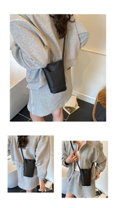 Minimalist black pebble leather vertical phone bag shown as a crossbody accessory