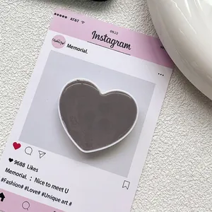 Gros plan d'un support de téléphone en forme de cœur gris foncé sur une carte esthétique