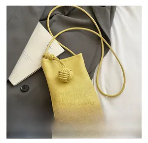 Detail of lemon yellow crossbody bag with litchi texture and woven knot decoration