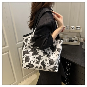 Detail of large cow print tote bag with black drawstring being worn by a model