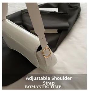 Detail of adjustable golden buckle and glossy white leather on minimalist shoulder bag