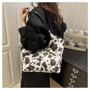 Detailed view of the cow print tote bag with black bow accents and slim shoulder straps