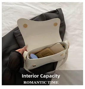 Internal capacity of white leather shoulder bag with gold clasp showing phone and wallet