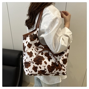 Detail of trendy cow print tote bag with brown leather handles and bow decoration