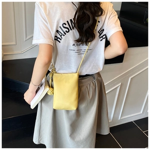 Detailed shot of yellow pebbled leather mini crossbody phone bag with knot strap on model