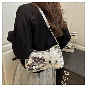 Close-up of silver sequin shoulder bag with metallic chain strap on model's shoulder