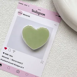 Gros plan d'un support de téléphone en résine en forme de cœur vert clair poli