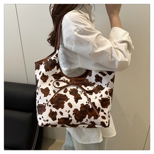Cow print faux fur tote bag with brown bow detail shown on a model's shoulder