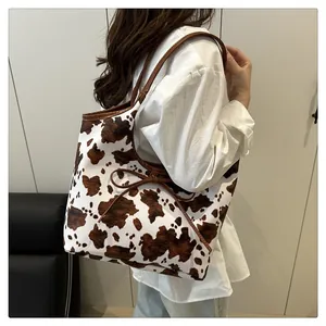 Detailed view of large cow print tote bag made of PU leather with decorative bow strap